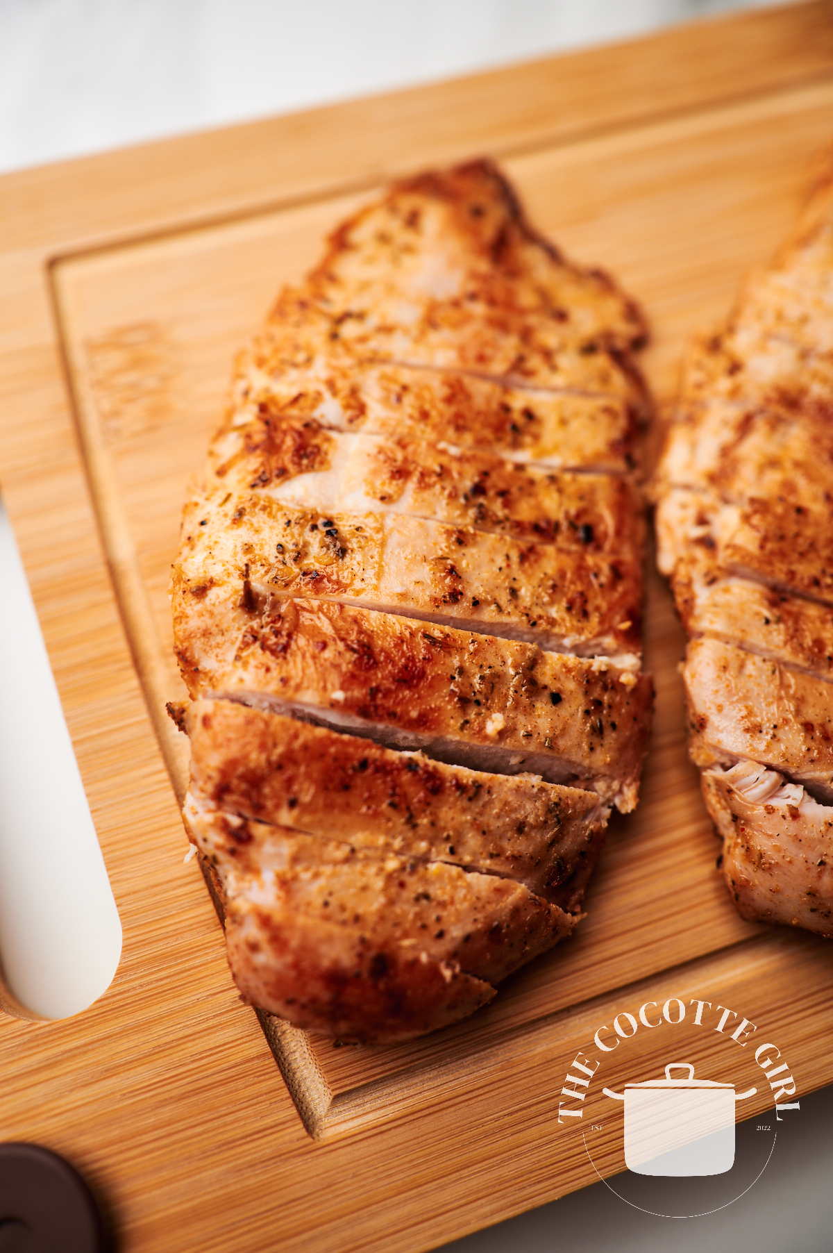 seasoned thinly sliced chicken breast on a wood cutting board